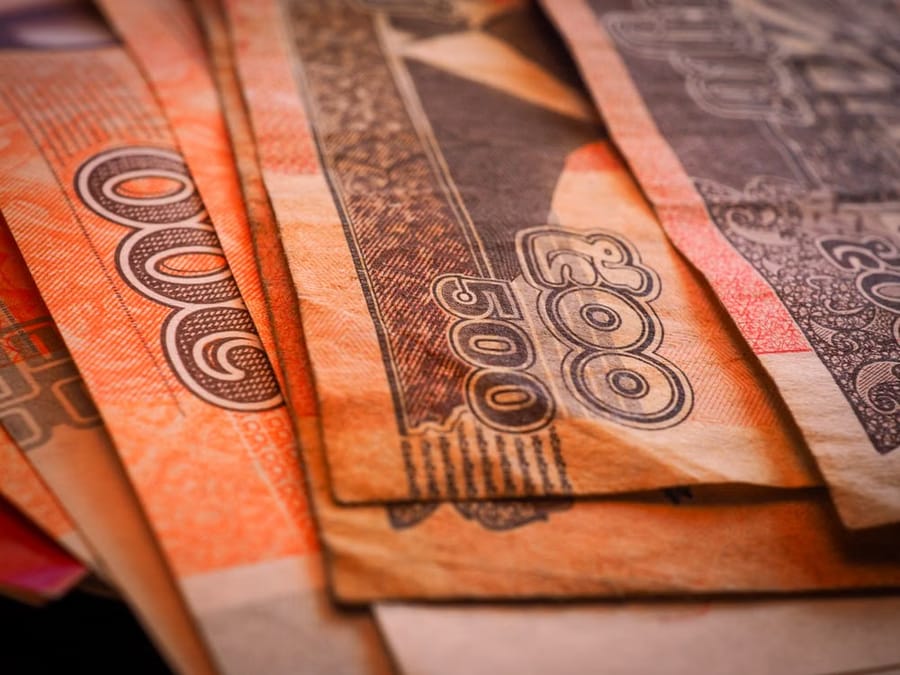 A close-up of orange-toned Cambodian riel banknotes fanned out on top of one another.
