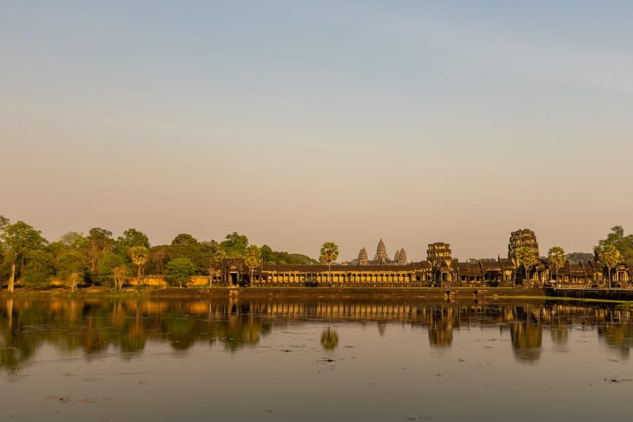 Angkor Wat’s outer gallery and towers glow at sunset, reflected in the surrounding moat.